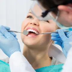 Uśmiechnięta pacjentka u dentysty. Zastanawiasz się nad lakowaniem zębów? Skutki uboczne są rzadkie, ale warto wiedzieć.