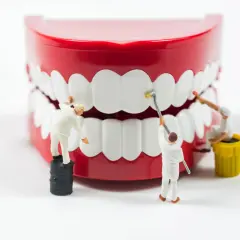 Miniaturowi pracownicy czyszczą gigantyczne zęby, pokazując, jak umyć zęby bez szczoteczki.