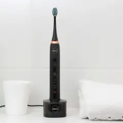 Czarna szczoteczka soniczna Eldom na ładowarce. Pamiętaj, co ile wymieniać końcówkę w szczoteczce sonicznej dla higieny.