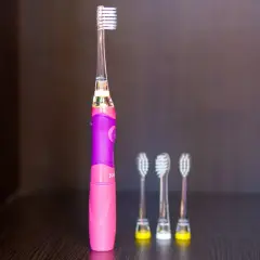 Różowa szczoteczka soniczna dla dzieci z trzema zapasowymi końcówkami.