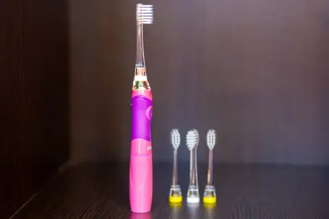 Różowa szczoteczka soniczna dla dzieci z trzema zapasowymi końcówkami.