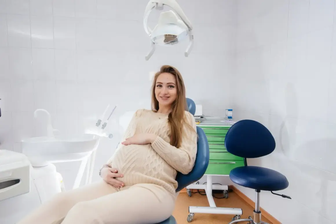 Uśmiechnięta ciężarna kobieta w gabinecie stomatologicznym. Odpowiedź na pytanie: czy można leczyć zęby w ciąży.