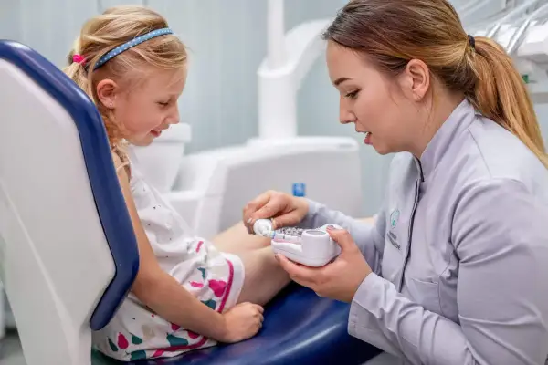 Dentystka pokazuje dziecku model szczęki, tłumacząc jak używać pasty z chlorkiem cetylopirydyniowym do higieny jamy ustnej.