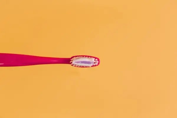 Różowa szczoteczka z biało-fioletową pastą. Uważaj na połknięcie pasty do zębów skutki mogą być nieprzyjemne.